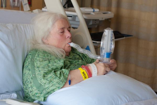 Woman suffering in bed with CPOD using a spirometer