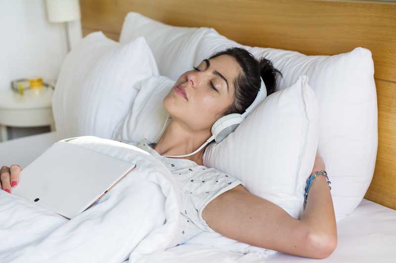 Woman trying to listen to music to help sleep