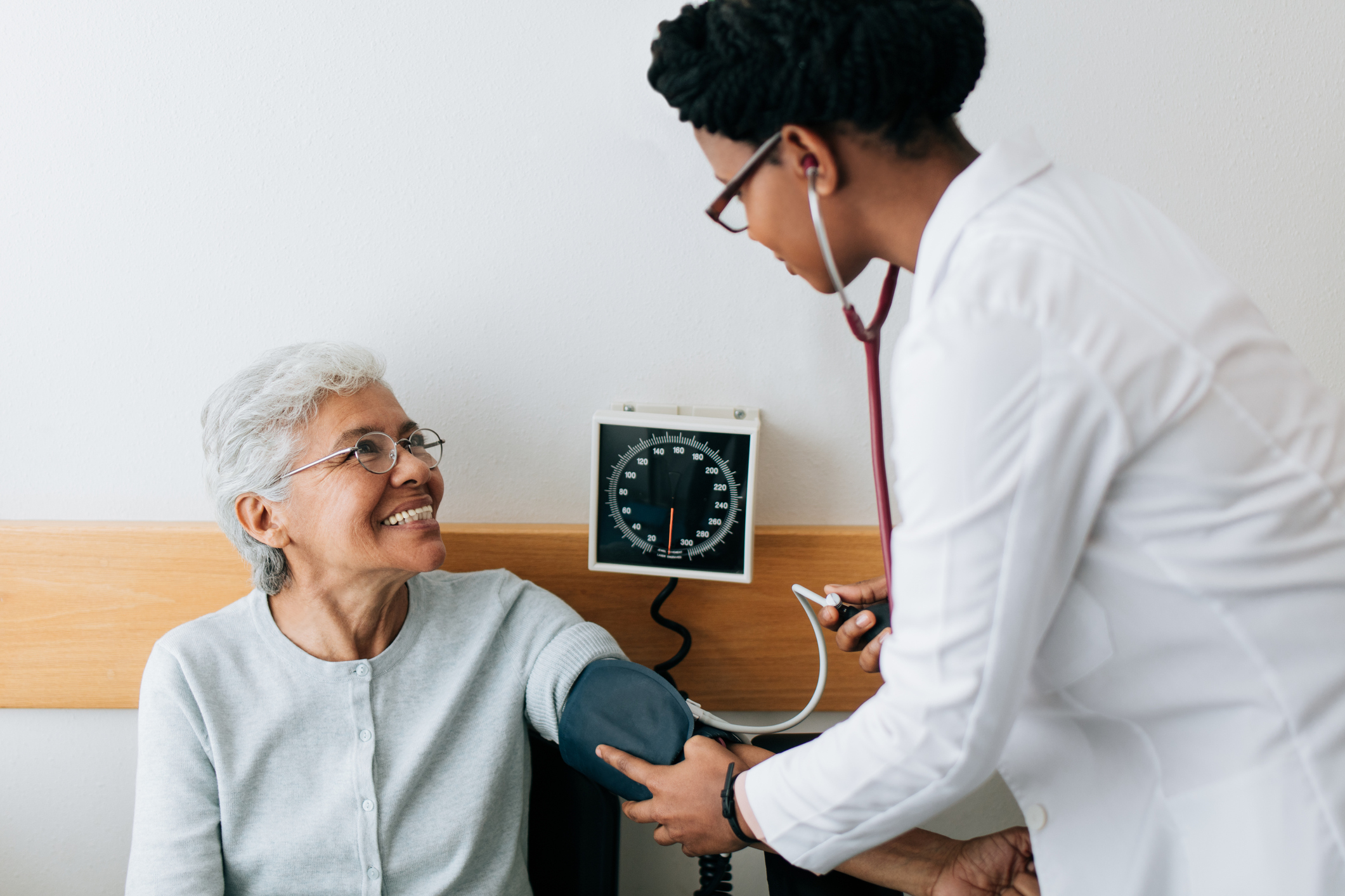 Female doctor checking blood pressure to senior patient