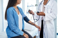 Doctor in white coat taking a patient's blood pressure