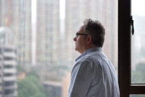 man looking outside at weather, seasonal depression symptoms